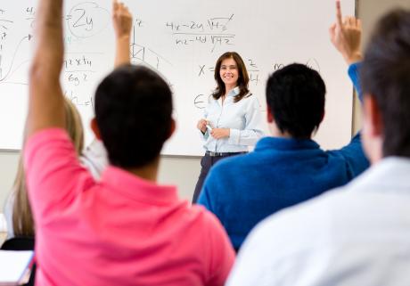 Students raising hands in a college classroom